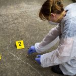 Woman forensic expert collects evidence at the crime scene